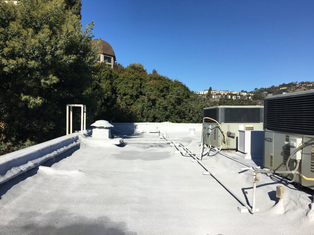 Foam roofing for multi-story building with HVAC systems installed on its flat roof
