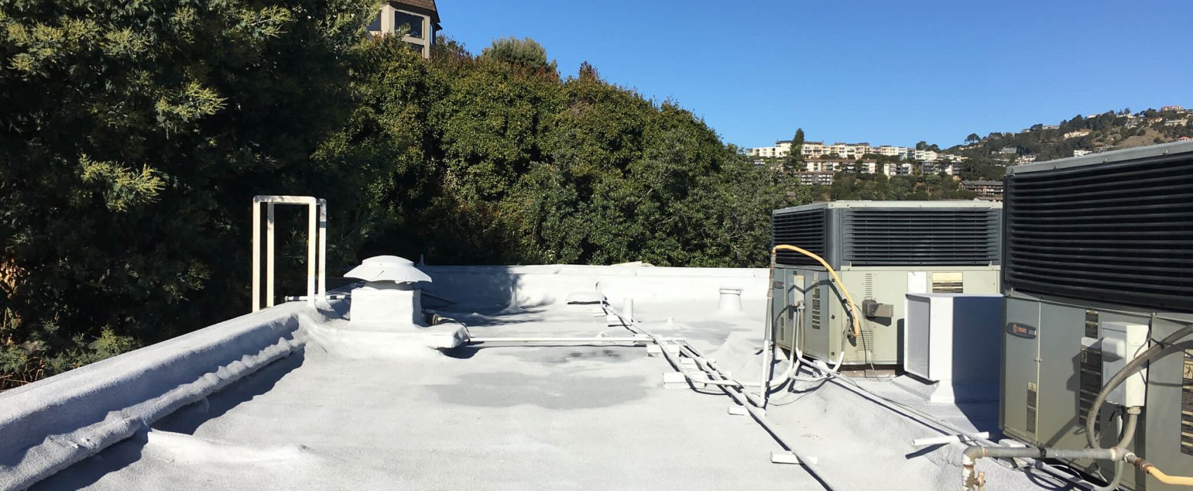 Foam roofing for multi-story building with HVAC systems installed on its flat roof